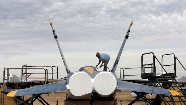 Preservation servicer Katy Shank sprays a sealing paint on a former NAVY Blue Angel F-18 at the 309th Aerospace Maintenance and Regeneration Group boneyard in Tucson, Ariz Preservation servicer Katy Shank sprays a sealing paint on a former NAVY Blue Angel F-18 at the 309th Aerospace Maintenance and Regeneration Group boneyard in Tucson, Ariz - Sputnik International