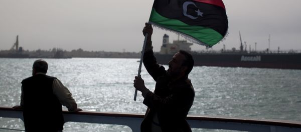 A man holds a pre Moammar Gadhafi flag. - Sputnik International