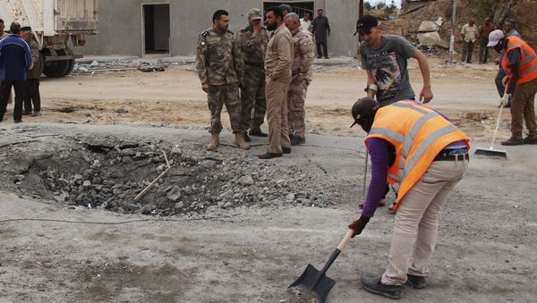 Workers clean the ground after a suicide car bomber blew himself up at a checkpoint in Dafniya outside Mistrata, Libya May 31, 2015 - Sputnik International