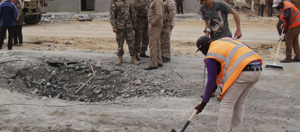 Workers clean the ground after a suicide car bomber blew himself up at a checkpoint in Dafniya outside Mistrata, Libya May 31, 2015 - Sputnik International