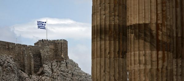 People stand next to a fluttering Greek national flag at the ancient site of the Athens' Acropolis as marble columns of the Temple of the Olympian Zeus are seen on the right June 7, 2015 - Sputnik International