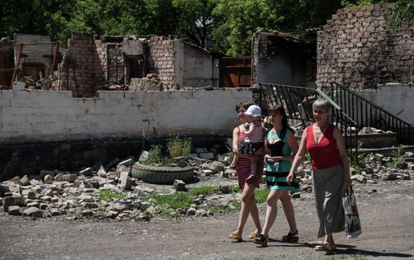 Residents walk in front of destroyed building as a result of shelling on June 8, 2015 in Novotoshkivske village, Donetsk region Residents walk in front of destroyed building as a result of shelling on June 8, 2015 in Novotoshkivske village, Donetsk region - Sputnik International
