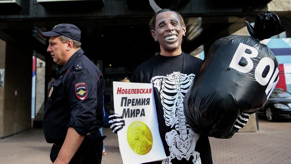 Russian Communist Party activist, wearing a mask depicting US President Barack Obama, holds a poster reading Nobel Peace Prize in one hand and a bag reading War in the other, takes part at a picket outside the UN mission in Moscow, Russia, Tuesday, Sept. 9, 2014 Russian Communist Party activist, wearing a mask depicting US President Barack Obama, holds a poster reading Nobel Peace Prize in one hand and a bag reading War in the other, takes part at a picket outside the UN mission in Moscow, Russia, Tuesday, Sept. 9, 2014 - Sputnik International