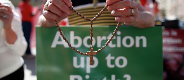 A file photo taken on July 10, 2013 shows a protester holding rosary beads and holding an anti-abortion placard in front of the gates of the Irish Parliament building in Dublin during a demonstration ahead of a vote to introduce abortion in limited cases where the mother's life is at risk - Sputnik International