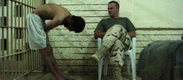 This is an image obtained by The Associated Press which shows a detainee bent over with his hands on the bars of a prison cell watched by a soldier in late 2003 at the Abu Ghraib prison in Baghdad, Iraq - Sputnik International