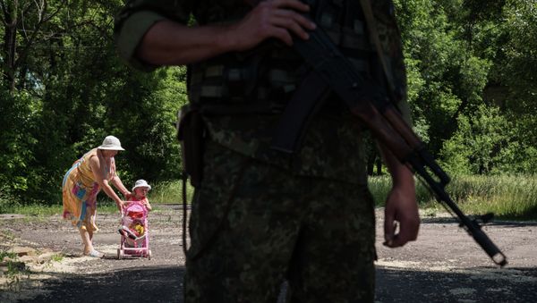 Woman walks with her child as Ukrainian serviceman stands guard on June 8, 2015 in Novotoshkivske village, Donetsk region Woman walks with her child as Ukrainian serviceman stands guard on June 8, 2015 in Novotoshkivske village, Donetsk region - Sputnik International