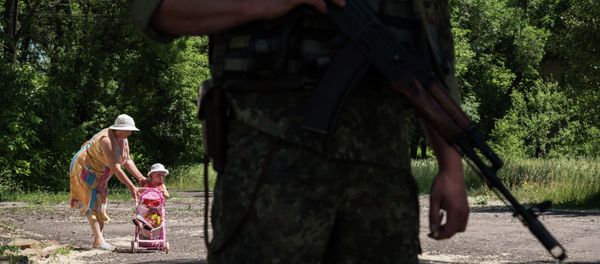 Woman walks with her child as Ukrainian serviceman stands guard on June 8, 2015 in Novotoshkivske village, Donetsk region Woman walks with her child as Ukrainian serviceman stands guard on June 8, 2015 in Novotoshkivske village, Donetsk region - Sputnik International