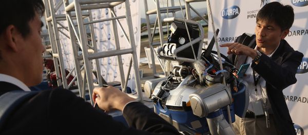 Roboticists take a closer look at the KAWADA Industries HRP-2 humanoid robot during the first day of the Defense Advanced Research Projects Agency (DARPA) Robotics Challenge at the Fairplex June 5, 2015 in Pomona, California - Sputnik International