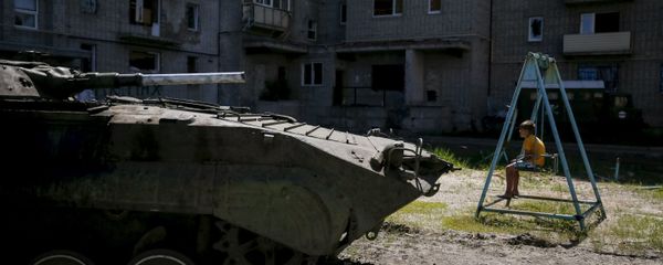 A boy sits on a swing near a building, which was damaged during fighting between Kiev and Donbass forces, as an armoured personnel carrier (APC) of the Ukrainian armed forces is seen nearby in Avdeyevka near Donetsk. June 7, 2015. - Sputnik International