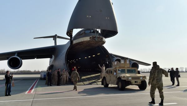 Ukrainian and US servicemen unload armoured cars from a plane at Kiev airport on March 25, 2015 during a welcoming ceremony of the first US plane delivery of non-lethal aid, including 10 Humvee vehicles - Sputnik International