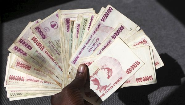 A man poses with a handful of Zimbabwean dollars at a bank in central Harare, June 15, 2015 - Sputnik International