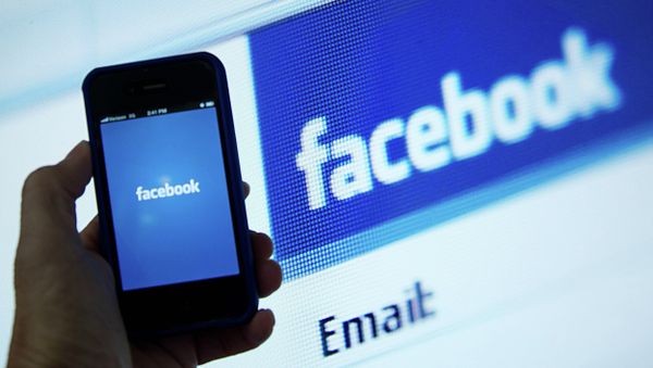In this May 10, 2012 file photo, a view of and Apple iPhone displaying the Facebook app's splash screen in front of the login page on a computer are shown in Washington, DC - Sputnik International