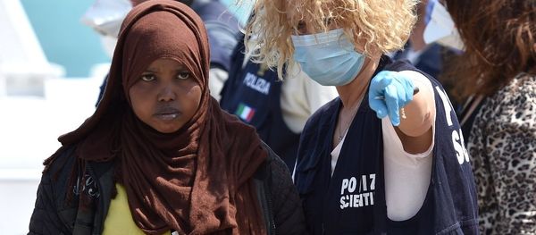 A forensic police officer gives indications to a woman as migrants arrived at Pozzallo's harbor near Ragusa, Sicily, Italy. - Sputnik International