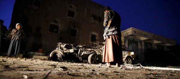An armed man looks at the wreckage of a car at the site of a car bomb attack in Yemen's catpital Sanaa June 17, 2015 - Sputnik International