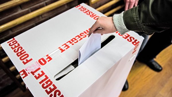 A voter casts a ballot in the voting box wrapped by tapes bearing letters that read: Sealed at a primary school in Copenhagen, Denmark, Thursday morning June 18, 2015 - Sputnik International