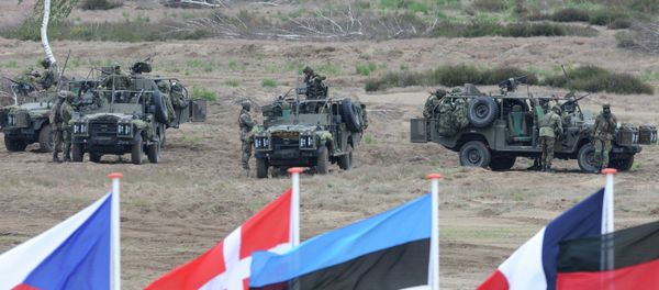 Flags wave in front of soldiers who take positions with their army vehicles during the NATO Noble Jump exercise on a training range near Swietoszow Zagan, Poland. file photo Flags wave in front of soldiers who take positions with their army vehicles during the NATO Noble Jump exercise on a training range near Swietoszow Zagan, Poland. file photo - Sputnik International