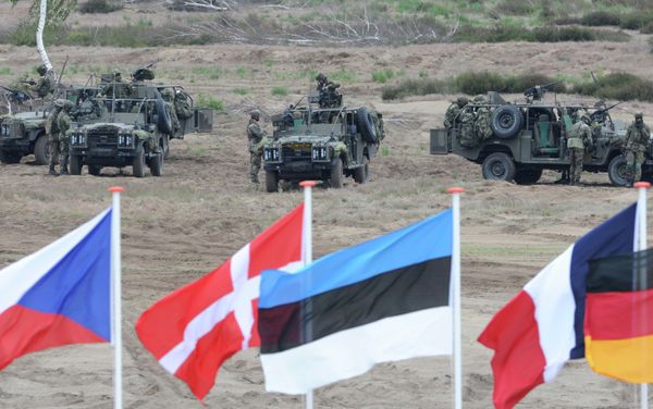 Flags wave in front of soldiers who take positions with their army vehicles during the NATO Noble Jump exercise on a training range near Swietoszow Zagan, Poland, Thursday, June 18, 2015 Flags wave in front of soldiers who take positions with their army vehicles during the NATO Noble Jump exercise on a training range near Swietoszow Zagan, Poland, Thursday, June 18, 2015 - Sputnik International
