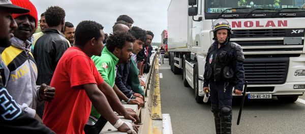 A French riot police officer (CRS) stands holdings his baton as illegal migrants wait to hide in lorries heading for England, in the French northern harbour of Calais, on June 17, 2015 - Sputnik International