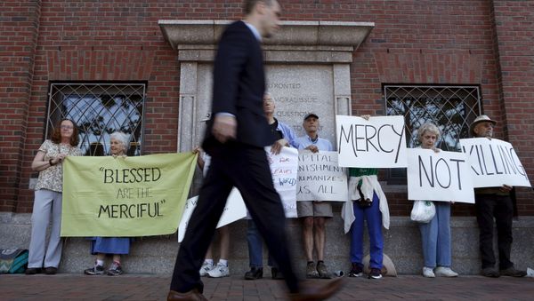 A pedestrian walks past death penalty protesters before the formal sentencing of convicted Boston Marathon bomber Dzhokhar Tsarnaev at the federal courthouse in Boston, Massachusetts June 24, 2015 - Sputnik International