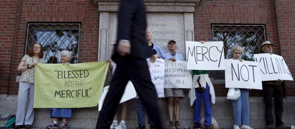 A pedestrian walks past death penalty protesters before the formal sentencing of convicted Boston Marathon bomber Dzhokhar Tsarnaev at the federal courthouse in Boston, Massachusetts June 24, 2015 - Sputnik International