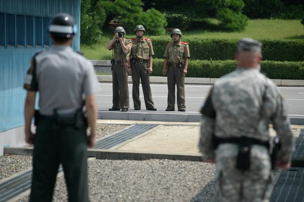 North Korean soldiers (C) take photos towards a South Korean soldier (L) and a US soldier (R) standing before the military demarcation line (lower C) seperating North and South Korea within the Joint Security Area (JSA) at Panmunjom on July 27, 2014 - Sputnik International