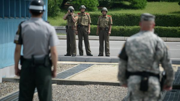 North Korean soldiers (C) take photos towards a South Korean soldier (L) and a US soldier (R) standing before the military demarcation line (lower C) seperating North and South Korea within the Joint Security Area (JSA) at Panmunjom on July 27, 2014 - Sputnik International