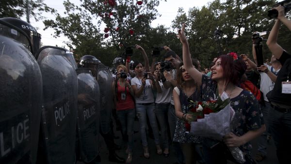 A protester throws rose petals in front of a line of riot police during a rally against a recent decision to raise public electricity prices in Yerevan, Armenia, June 23, 2015 A protester throws rose petals in front of a line of riot police during a rally against a recent decision to raise public electricity prices in Yerevan, Armenia, June 23, 2015 - Sputnik International
