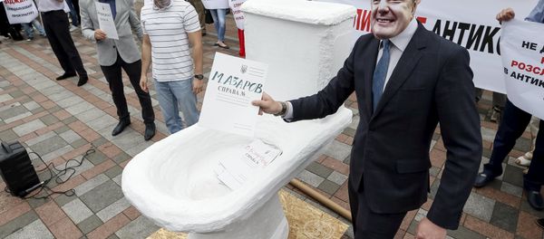 An activist wearing a mask depicting Ukrainian President Petro Poroshenko (R) places mock criminal files in a fake toilet during a performance to protest against what the activists said was corruption in the government, in front of the parliament building in Kiev, Ukraine, June 17, 2015 - Sputnik International