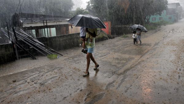 A woman carries her children in the rain as she walks by homes destroyed by flooding in Alajuela, Costa Rica - Sputnik International