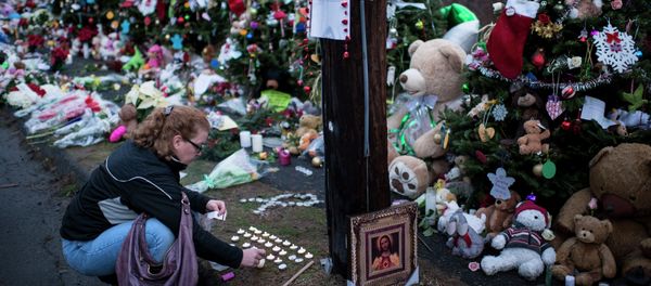 A woman lights candles at a makeshift memorial near the entrance to the grounds of Sandy Hook Elementary School on December 18, 2012 in Newtown, Connecticut A woman lights candles at a makeshift memorial near the entrance to the grounds of Sandy Hook Elementary School on December 18, 2012 in Newtown, Connecticut - Sputnik International