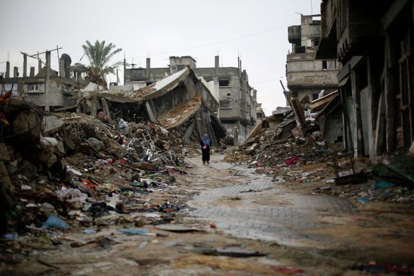 A Palestinian woman walks in the rain past houses that were destroyed during the 50-day Gaza war between Israel and Hamas-led militants, on November 24, 2014, in Gaza City - Sputnik International