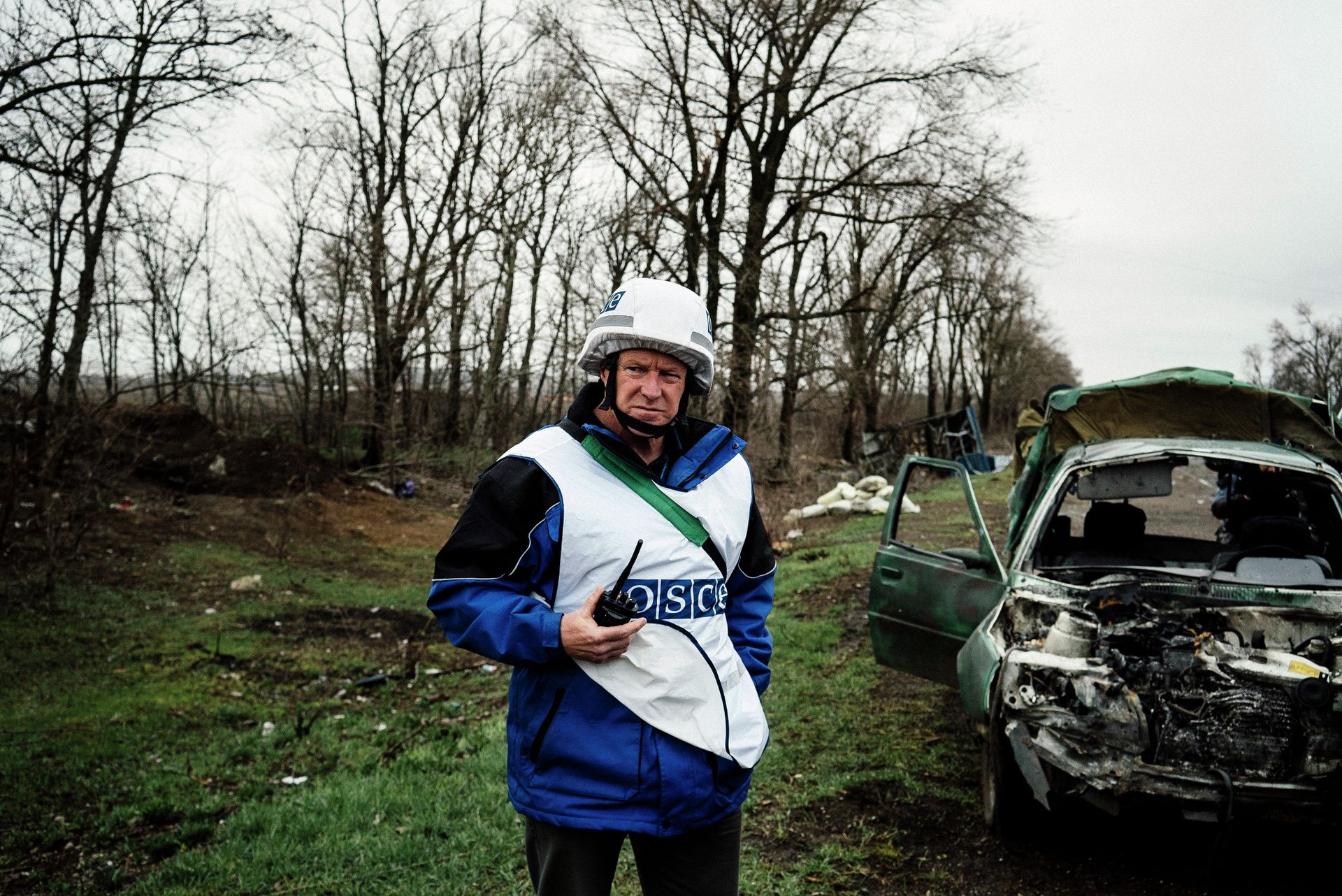 An International observer of the Organization for Security and Co-operation in Europe (OSCE) stands next to a destroyed car after shelling during an inspection tour near the village of Shirokino - Sputnik International, 1920, 01.12.2022
