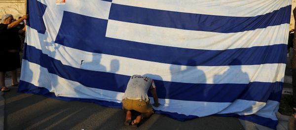 A protester kneels to pay his respect in front of a Greek flag during an anti-austerity rally in Athens, Greece, June 29, 2015 - Sputnik International