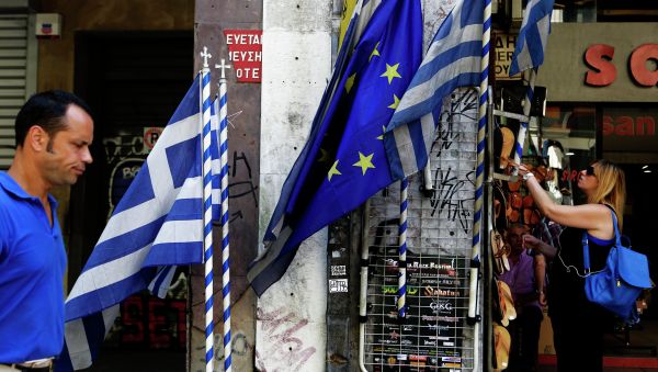 A woman looks at sandals from a shop as an a man passes by Greek and European Union flags in central Athens, Wednesday, July 8, 2015 A woman looks at sandals from a shop as an a man passes by Greek and European Union flags in central Athens, Wednesday, July 8, 2015 - Sputnik International