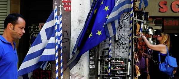 A woman looks at sandals from a shop as an a man passes by Greek and European Union flags in central Athens, Wednesday, July 8, 2015 A woman looks at sandals from a shop as an a man passes by Greek and European Union flags in central Athens, Wednesday, July 8, 2015 - Sputnik International