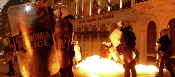 Riot police stand amongst the flames from exploded petrol bombs thrown by a small group of anti-austerity demonstrators in front of parliament in Athens, Greece July 15, 2015 Riot police stand amongst the flames from exploded petrol bombs thrown by a small group of anti-austerity demonstrators in front of parliament in Athens, Greece July 15, 2015 - Sputnik International