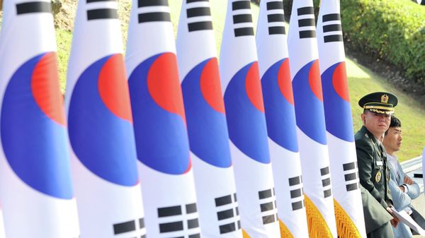 A South Korean military officer (R) stands next to a line of national flags during a ceremony to mark the 64th Korea Armed Forces Day at the military headquarters in Gyeryong, about 140 km south of Seoul, on September 25, 2012 - Sputnik International
