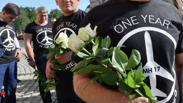 People wearing t-shirts bearing a drawing of a plane and slogans reading MH 17, One year in the skies hold flowers to the Dutch embassy in Kiev on July 17, 2015 in memory of the people who died in the crash of Malaysian Airlines flight MH17 People wearing t-shirts bearing a drawing of a plane and slogans reading MH 17, One year in the skies hold flowers to the Dutch embassy in Kiev on July 17, 2015 in memory of the people who died in the crash of Malaysian Airlines flight MH17 - Sputnik International