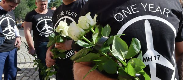 People wearing t-shirts bearing a drawing of a plane and slogans reading  MH 17, One year in the skies hold flowers to the Dutch embassy in Kiev on July 17, 2015 in memory of the people who died in the crash of Malaysian Airlines flight MH17 - Sputnik International