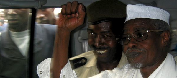 Former Chad President Hissene Habre (R) raises his fist in the air as he leaves a court in Dakar escorted by a Senegalese policeman in this November 25, 2005 file photo - Sputnik International