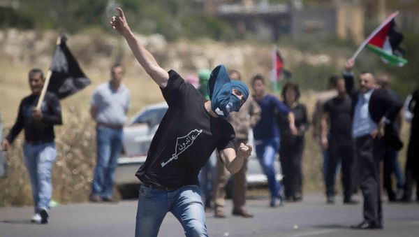 A Palestinian throws a stone at Israeli troops during clashes after a rally marking Nakba Day at Hawara checkpoint near the West Bank city of Nablus. - Sputnik International