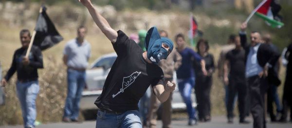 A Palestinian throws a stone at Israeli troops during clashes after a rally marking Nakba Day at Hawara checkpoint near the West Bank city of Nablus. - Sputnik International