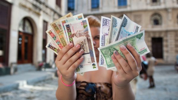 A Cuban shows Cuban Pesos CUP (Left hand) and Convertible Pesos CUC (Right hand) A Cuban shows Cuban Pesos CUP (Left hand) and Convertible Pesos CUC (Right hand) - Sputnik International