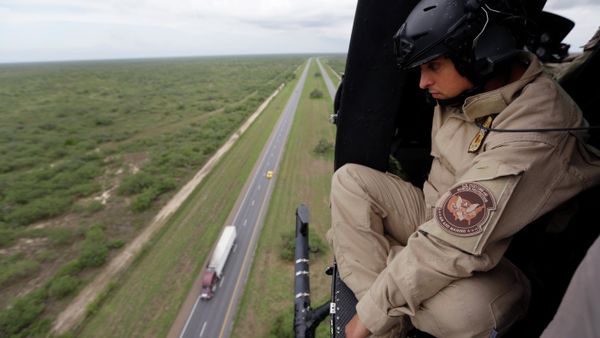 A US Customs and Border Protection Air and Marine agent pears out of the open door of a helicopter during a patrol flight near the Texas-Mexico border. A US Customs and Border Protection Air and Marine agent pears out of the open door of a helicopter during a patrol flight near the Texas-Mexico border. - Sputnik International