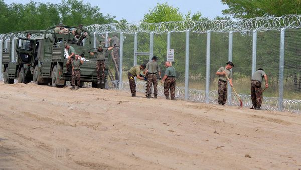 A picture is taken on July 18, 2015 shows soldiers of the Hungarian Army's technical unit finish the first completed elements of the 150 meter-long metal fence at the Hungarian-Serbian border nearby Morahalom village A picture is taken on July 18, 2015 shows soldiers of the Hungarian Army's technical unit finish the first completed elements of the 150 meter-long metal fence at the Hungarian-Serbian border nearby Morahalom village - Sputnik International
