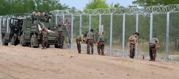 A picture is taken on July 18, 2015 shows soldiers of the Hungarian Army's technical unit finish the first completed elements of the 150 meter-long metal fence at the Hungarian-Serbian border nearby Morahalom village - Sputnik International