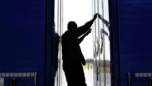 A migrant stands between two trailers of a lorry as he attempts to cross the English Channel, in Calais, northern France, Wednesday, June 24, 2015. - Sputnik International