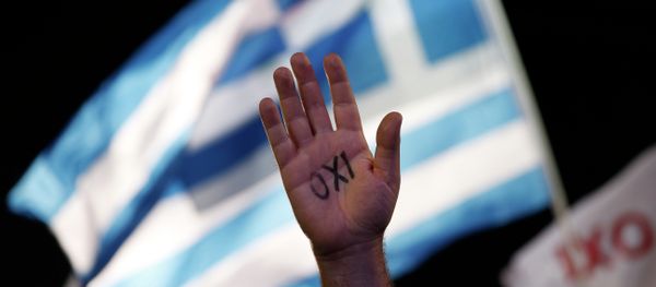A demonstrator raises his hand with the Greek word ''No'' written on it in front of a Greek flag during a rally in support of the no vote to an upcoming referendum called by Premier Alexis Tsipras on whether to accept the terms of an international bailout, in Athens, in this photo dated Friday, July 3, 2015. - Sputnik International