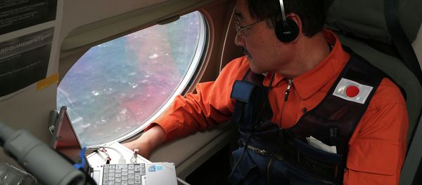 Communications specialist Hidetaka Sato on a Japan Coast Guard Gulfstream aircraft, looks out of a window searching for the missing Malaysia Airlines Flight MH370 in Southern Indian Ocean, near Australia, Tuesday, April 1, 2014. Communications specialist Hidetaka Sato on a Japan Coast Guard Gulfstream aircraft, looks out of a window searching for the missing Malaysia Airlines Flight MH370 in Southern Indian Ocean, near Australia, Tuesday, April 1, 2014. - Sputnik International