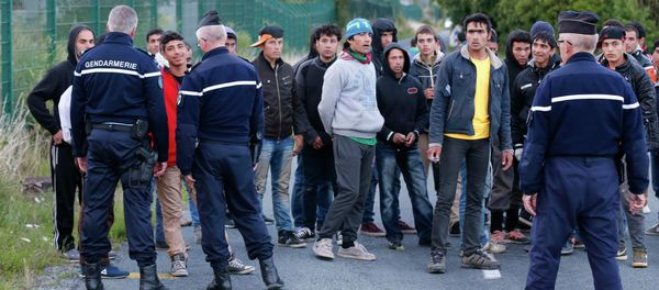 French gendarmes block migrants along a road to prevent them access to train tracks which lead to the Channel Tunnel in Frethun, near Calais, France - Sputnik International